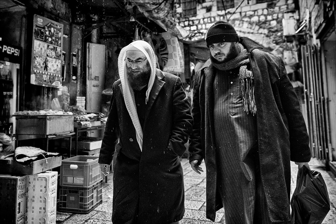 Two people walking among stalls on a narrow street.